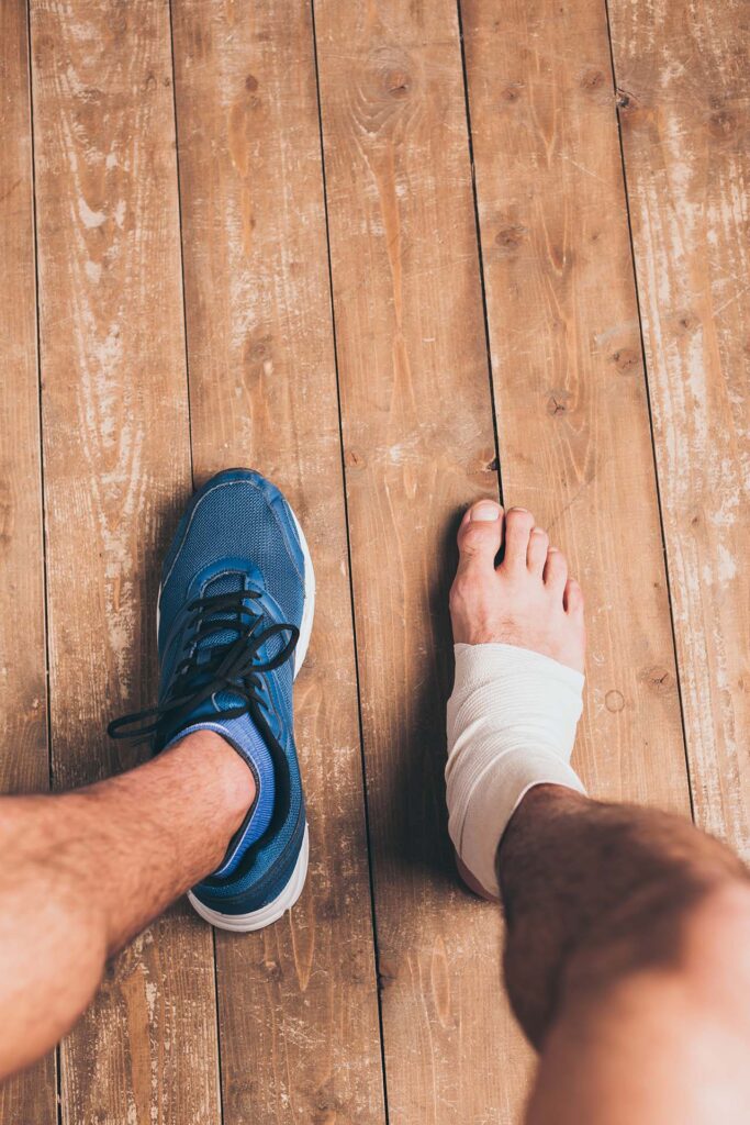 partial view of injured sportsman sitting in one sneaker with on